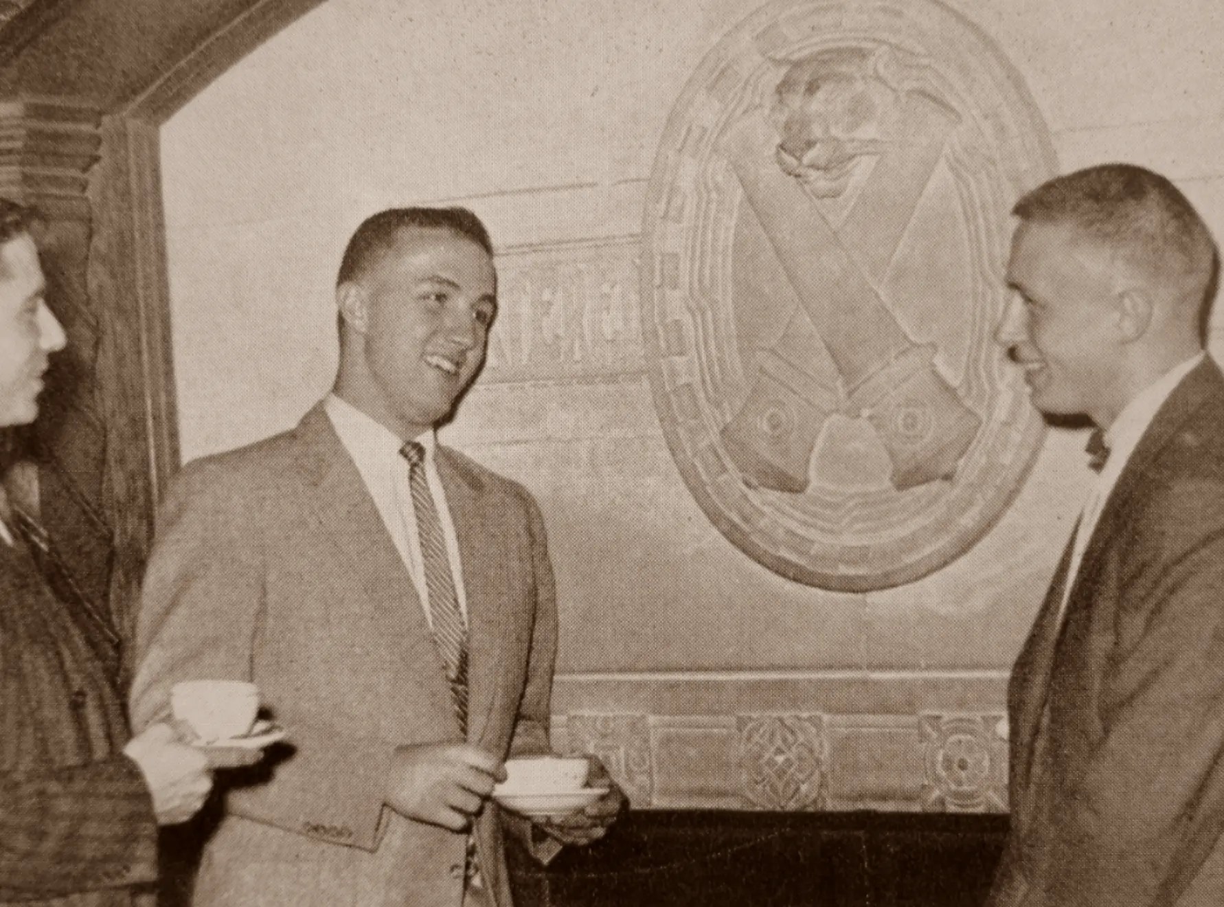 Historical photo of members in front of the CDE living room fireplace.