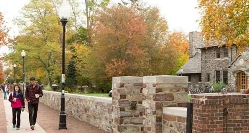 Two students walking in front of the CDE building wall.